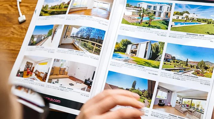 person reading ads with real estate marketing images